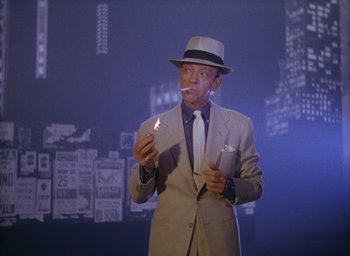 Movie still from “The Band Wagon” (1953), directed by Vincente Minnelli – A man in a suit and hat smoking a cigarette; Medium shot, Low angle