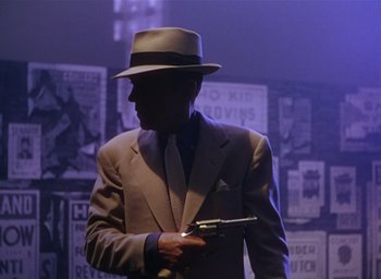 Movie still from “The Band Wagon” (1953), directed by Vincente Minnelli – A man in a suit and hat holding a gun in his hand; Medium shot, Low angle