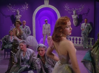Movie still from “The Band Wagon” (1953), directed by Vincente Minnelli – A group of people sitting in a room with purple walls; Wide shot, Low angle