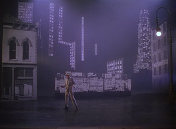 Movie still from “The Band Wagon” (1953), directed by Vincente Minnelli – A man and a woman walking on a stage in front of buildings; Extreme Wide shot, High angle