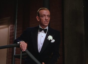 Movie still from “The Band Wagon” (1953), directed by Vincente Minnelli – A man in a tuxedo standing next to a railing; Medium shot, Low angle