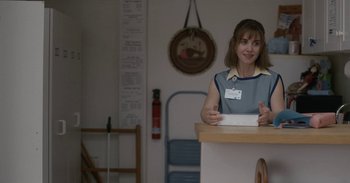 Movie still from “Horse Girl” (2020), directed by Jeff Baena – A woman sitting at a counter holding a piece of paper; Medium shot, Over the shoulder angle