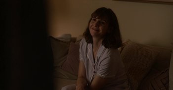 Movie still from “Horse Girl” (2020), directed by Jeff Baena – A woman sitting on top of a couch in a living room; Medium shot, Over the shoulder angle