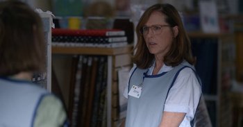 Movie still from “Horse Girl” (2020), directed by Jeff Baena – A woman wearing glasses standing in front of a bookshelf; Medium shot, Over the shoulder angle