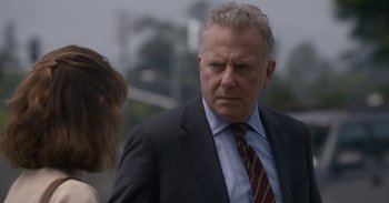 Movie still from “Horse Girl” (2020), directed by Jeff Baena – An older man wearing a suit and tie; Close Up shot, Over the shoulder angle