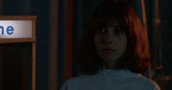 Movie still from “Horse Girl” (2020), directed by Jeff Baena – A young woman is standing in a dark room; Close Up shot, Over the shoulder angle