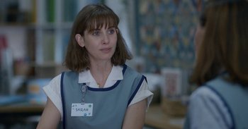 Movie still from “Horse Girl” (2020), directed by Jeff Baena – A woman with a name tag is standing in front of a wall; Close Up shot, Over the shoulder angle