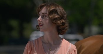 Movie still from “Horse Girl” (2020), directed by Jeff Baena – A young woman with brown hair wearing an orange dress; Close Up shot, Over the shoulder angle