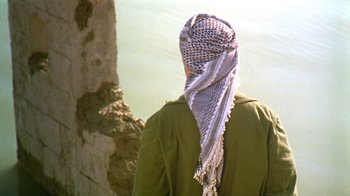 Movie still from “The Bandit” (1996), directed by Yavuz Turgul – A person with a head covering on a cliff face; Medium shot, Over the shoulder angle