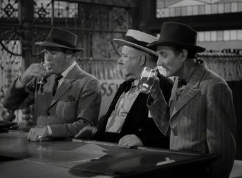 Movie still from “The Bank Dick” (1940), directed by Edward F. Cline – A group of men sitting at a table with a drink; Medium shot, Low angle