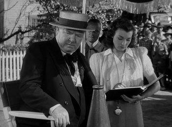 Movie still from “The Bank Dick” (1940), directed by Edward F. Cline – An old photo of two men and a woman; Medium shot, Low angle