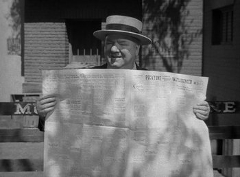 Movie still from “The Bank Dick” (1940), directed by Edward F. Cline – A black and white photo of a man holding a newspaper; Close Up shot, Low angle