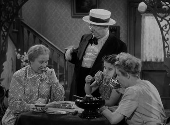 Movie still from “The Bank Dick” (1940), directed by Edward F. Cline – An old photo of a family sitting at a dinner table; Medium shot, High angle
