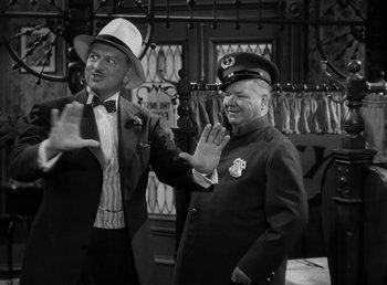 Movie still from “The Bank Dick” (1940), directed by Edward F. Cline – Two men in suits and hats wave at the camera; Medium shot, Over the shoulder angle