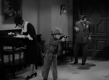 Movie still from “The Bank Dick” (1940), directed by Edward F. Cline – An old photo of a man and a woman and a boy with a gun; Wide shot, High angle
