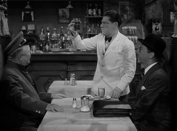 Movie still from “The Bank Dick” (1940), directed by Edward F. Cline – An old photo of two men sitting at a table; Medium shot, Over the shoulder angle