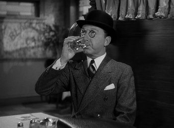 Movie still from “The Bank Dick” (1940), directed by Edward F. Cline – A man in a suit and hat drinking a glass of wine; Close Up shot, Low angle