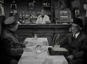 Movie still from “The Bank Dick” (1940), directed by Edward F. Cline – A man and a woman sitting at a table in front of a bar; Medium shot, Over the shoulder angle