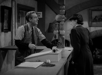 Movie still from “The Bank Dick” (1940), directed by Edward F. Cline – A man and a woman at a counter in an old photo; Medium shot, Over the shoulder angle