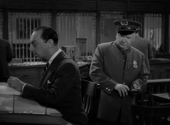 Movie still from “The Bank Dick” (1940), directed by Edward F. Cline – Two men in suits and hats are sitting at a table; Medium shot, Low angle