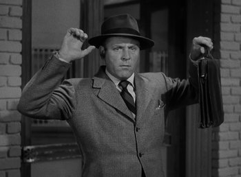 Movie still from “The Bank Dick” (1940), directed by Edward F. Cline – A black and white photo of a man in a suit and hat; Medium shot, Low angle