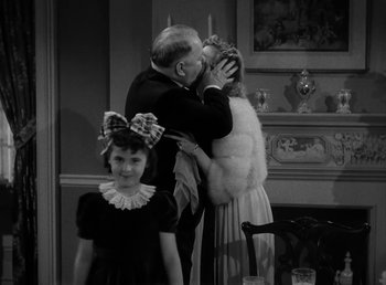 Movie still from “The Bank Dick” (1940), directed by Edward F. Cline – An older man kissing a young woman on the cheek; Medium shot, Over the shoulder angle