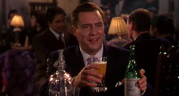 Movie still from “The Barefoot Contessa” (1954), directed by Joseph L. Mankiewicz – A man sitting at a table holding a glass of beer; Close Up shot, Over the shoulder angle