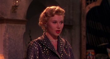Movie still from “The Barefoot Contessa” (1954), directed by Joseph L. Mankiewicz – A woman with blonde curly hair wearing a black jacket; Close Up shot, Over the shoulder angle