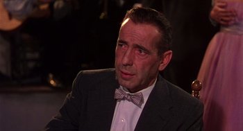 Movie still from “The Barefoot Contessa” (1954), directed by Joseph L. Mankiewicz – A person wearing a suit and a bow tie; Close Up shot, Over the shoulder angle