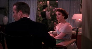 Movie still from “The Barefoot Contessa” (1954), directed by Joseph L. Mankiewicz – A woman sitting at a table in front of a man in a suit; Medium shot, Over the shoulder angle