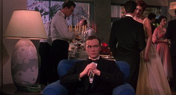 Movie still from “The Barefoot Contessa” (1954), directed by Joseph L. Mankiewicz – A man sitting in a chair in front of a table; Medium shot, Low angle
