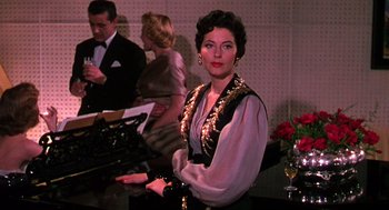 Movie still from “The Barefoot Contessa” (1954), directed by Joseph L. Mankiewicz – A woman standing in front of a bar with a glass of wine; Medium shot, Low angle