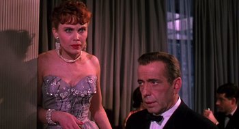 Movie still from “The Barefoot Contessa” (1954), directed by Joseph L. Mankiewicz – A woman standing next to a man wearing a tuxedo; Close Up shot, Over the shoulder angle