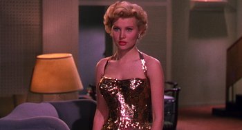 Movie still from “The Barefoot Contessa” (1954), directed by Joseph L. Mankiewicz – A woman in a gold dress standing in front of a couch; Medium shot, Low angle