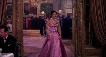 Movie still from “The Barefoot Contessa” (1954), directed by Joseph L. Mankiewicz – A woman in a pink dress standing in front of a crowd; Wide shot, Low angle
