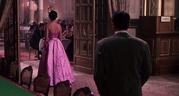 Movie still from “The Barefoot Contessa” (1954), directed by Joseph L. Mankiewicz – A man and a woman in formal wear standing in front of a dining room; Wide shot, Over the shoulder angle