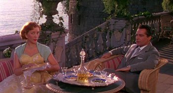 Movie still from “The Barefoot Contessa” (1954), directed by Joseph L. Mankiewicz – Two people sitting at a table with a tray of wine glasses; Medium shot, High angle