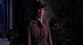 Movie still from “The Barefoot Contessa” (1954), directed by Joseph L. Mankiewicz – A man wearing a hat and a trench coat; Medium shot, Low angle