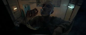 Movie still from “The Beach” (2000), directed by Danny Boyle – A man smoking a cigarette in a dark room; Close Up shot, Low angle