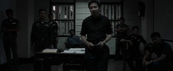 Movie still from “The Beach” (2000), directed by Danny Boyle – A man standing in front of a group of people; Medium shot, Low angle