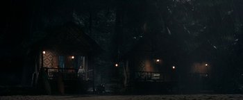 Movie still from “The Beach” (2000), directed by Danny Boyle – People are sitting outside of a house at night; Extreme Wide shot, Low angle