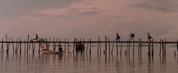 Movie still from “The Beach” (2000), directed by Danny Boyle – A man sitting on top of a wooden pier; Extreme Wide shot, Low angle