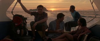 Movie still from “The Beach” (2000), directed by Danny Boyle – A group of young men sitting on top of a boat in the ocean; Wide shot, Low angle