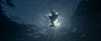 Movie still from “The Beach” (2000), directed by Danny Boyle – A person is swimming in the water under the water; Extreme Wide shot, Overhead angle