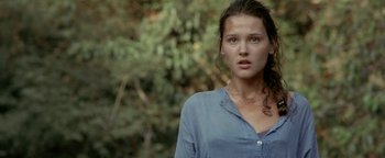 Movie still from “The Beach” (2000), directed by Danny Boyle – A woman in a blue shirt is standing in front of a tree; Close Up shot, Low angle