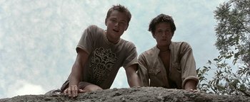 Movie still from “The Beach” (2000), directed by Danny Boyle – Two young men sitting on top of a hill; Medium shot, Low angle
