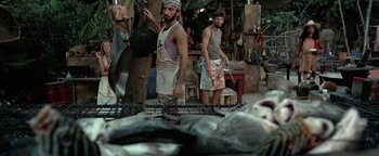 Movie still from “The Beach” (2000), directed by Danny Boyle – Two men standing next to each other in front of fish; Wide shot, High angle