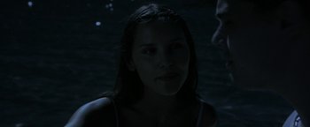 A woman is standing in the dark looking at the camera