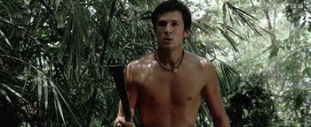 Movie still from “The Beach” (2000), directed by Danny Boyle – A shirtless man holding an axe in the woods; Medium shot, Low angle