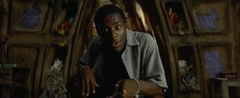 Movie still from “The Beach” (2000), directed by Danny Boyle – A man in a gray shirt is holding a pair of handcuffs; Close Up shot, Low angle
